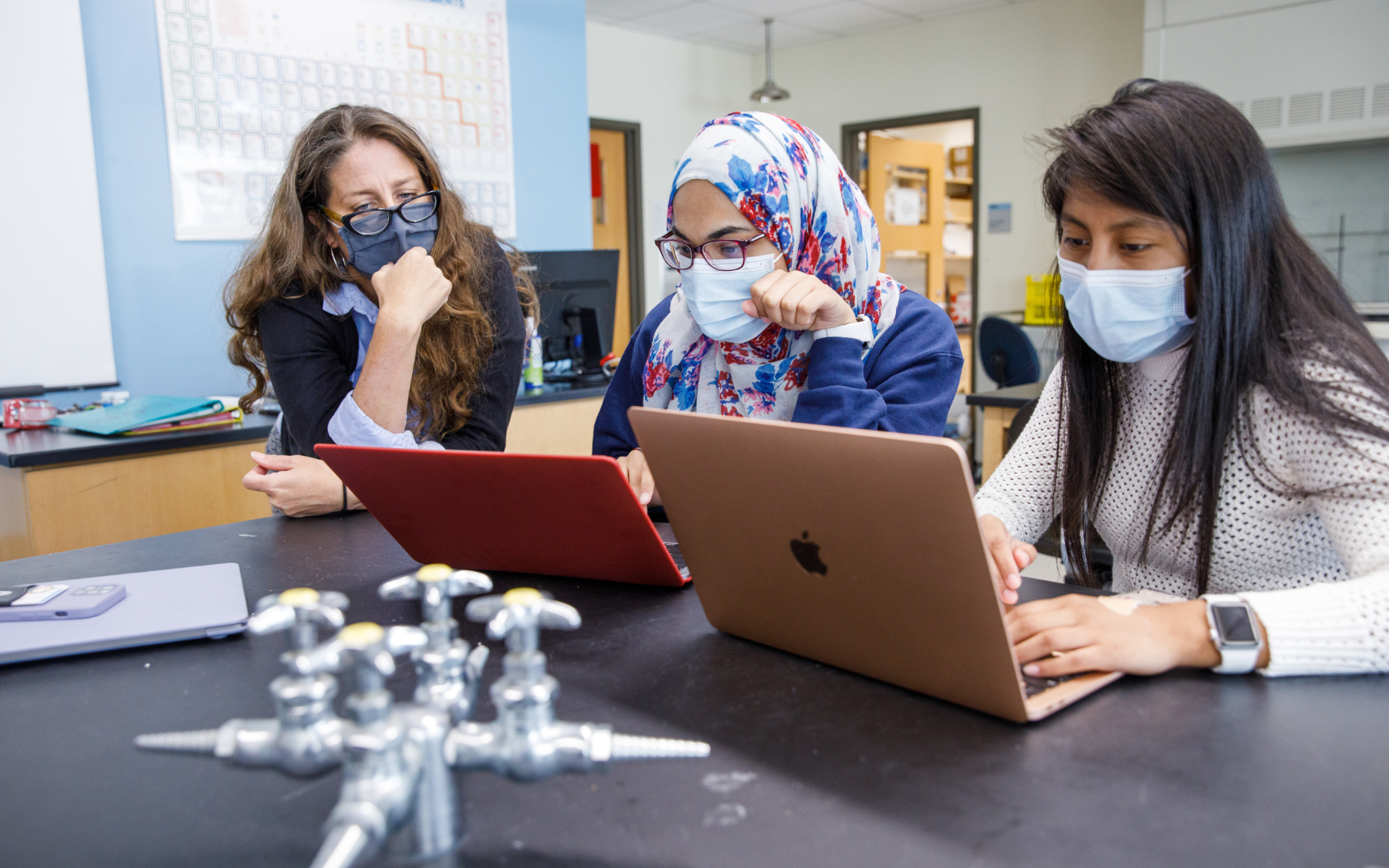 Professor and two students reviewing information on a computer screen in a science lab