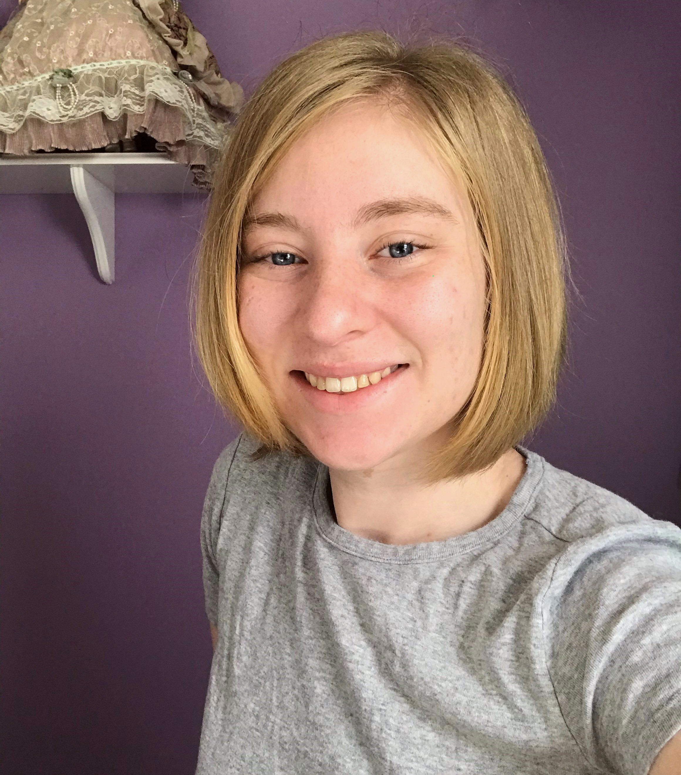 Erica, wearing a gray shirt, smiling with a purple wall behind her. 